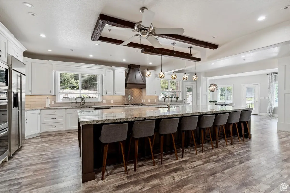 Kitchen featuring plenty of natural light, light wood-style flooring, custom range hood, beam ceiling, and recessed lighting