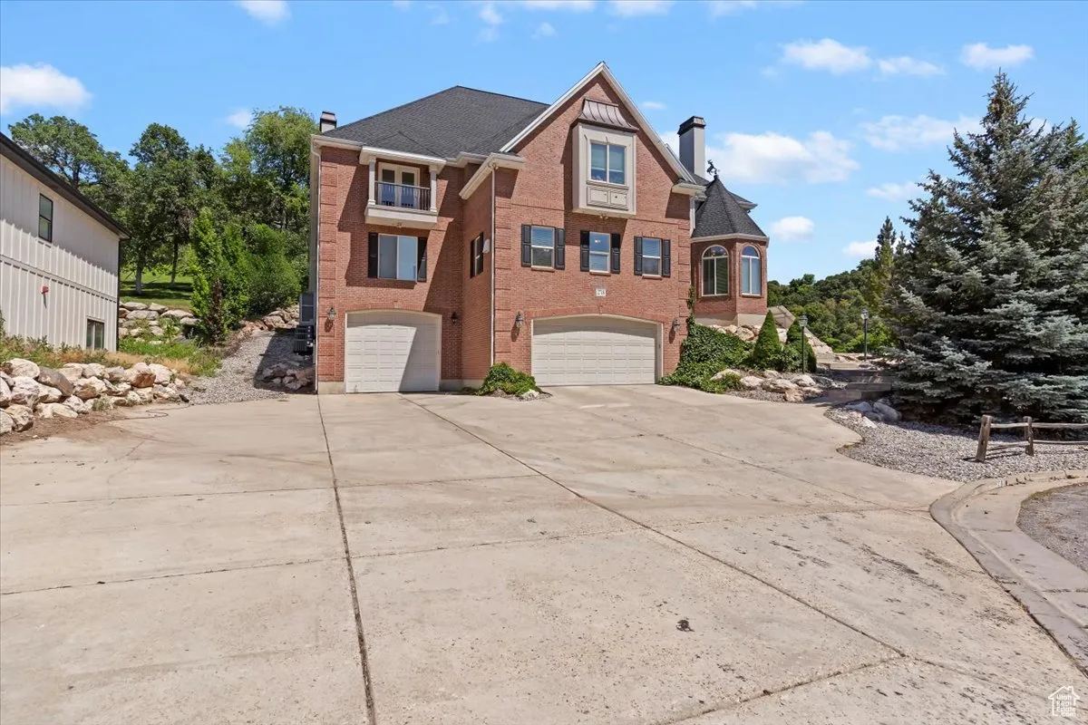 View of front facade with a chimney, a garage, driveway, and brick siding