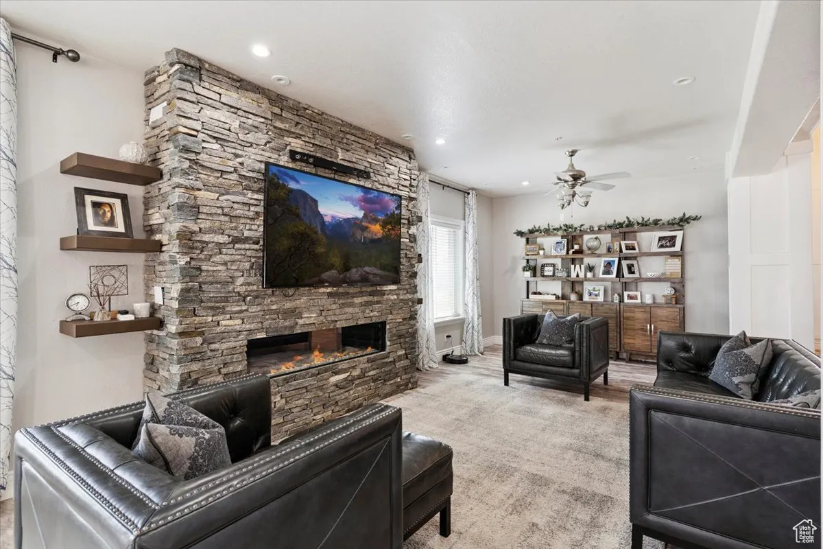 Living room with ceiling fan, a stone fireplace, and recessed lighting
