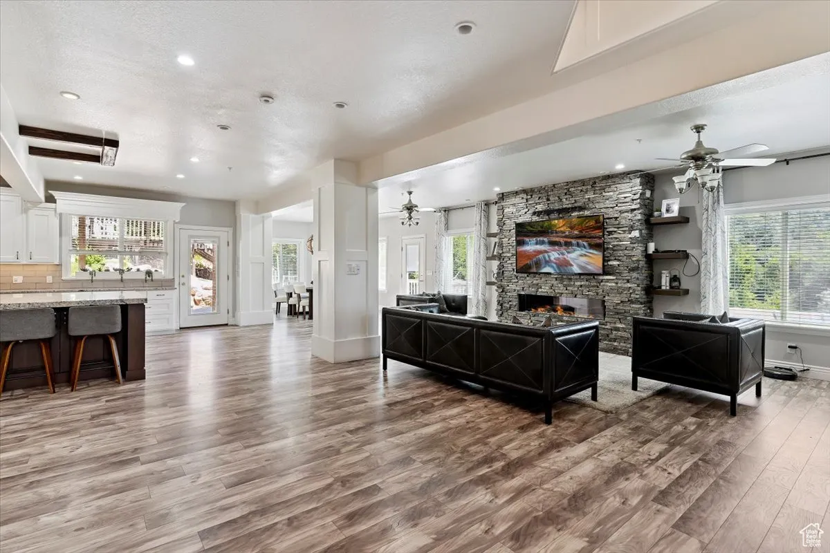 Living area with light wood-style flooring, a ceiling fan, a fireplace, plenty of natural light, and recessed lighting