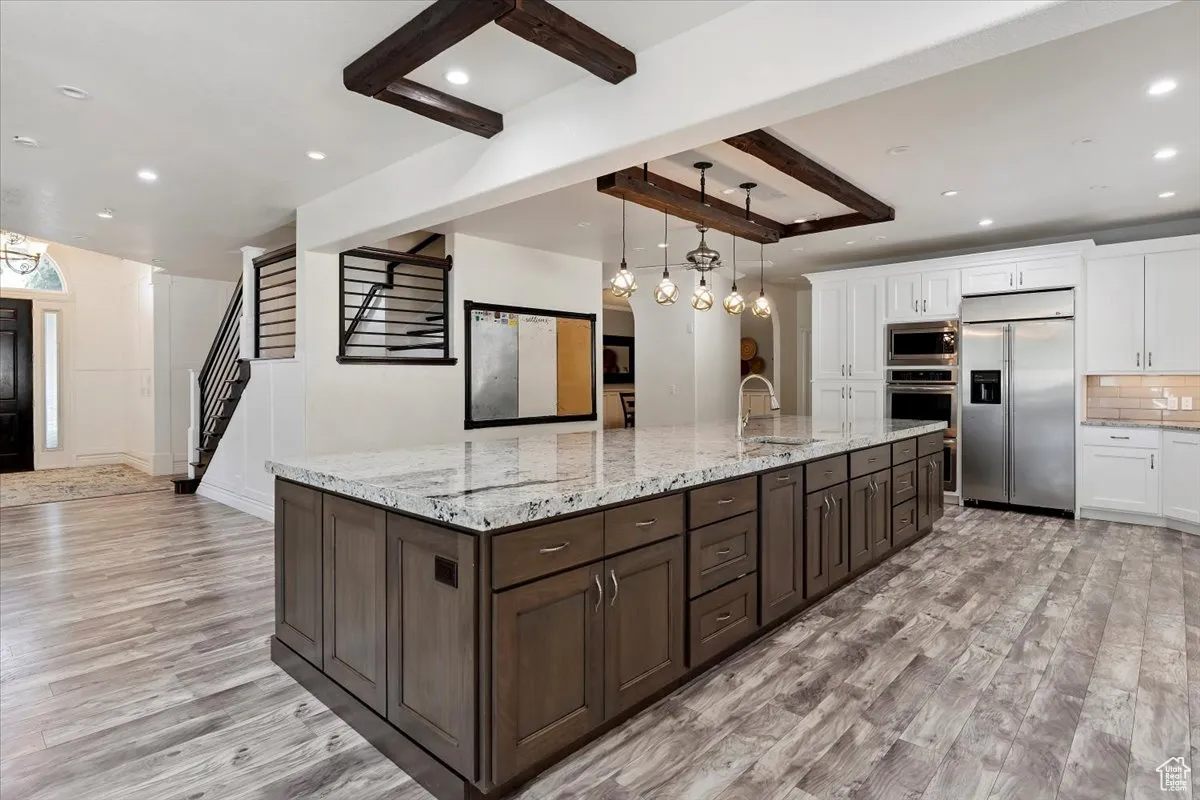 Kitchen with built in appliances, light wood-style flooring, white cabinetry, recessed lighting, and dark brown cabinetry