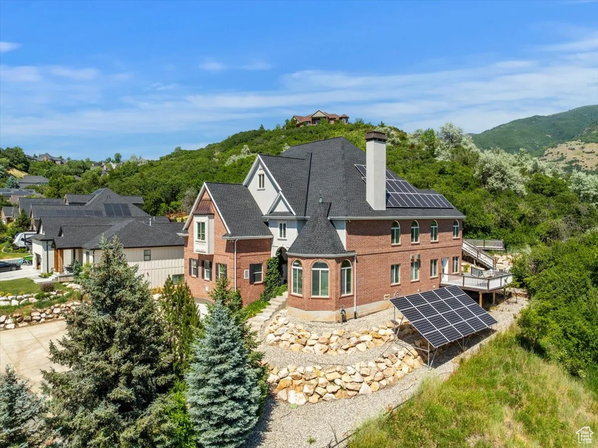 Rear view of property with ground mounted solar panels, a chimney, and brick siding