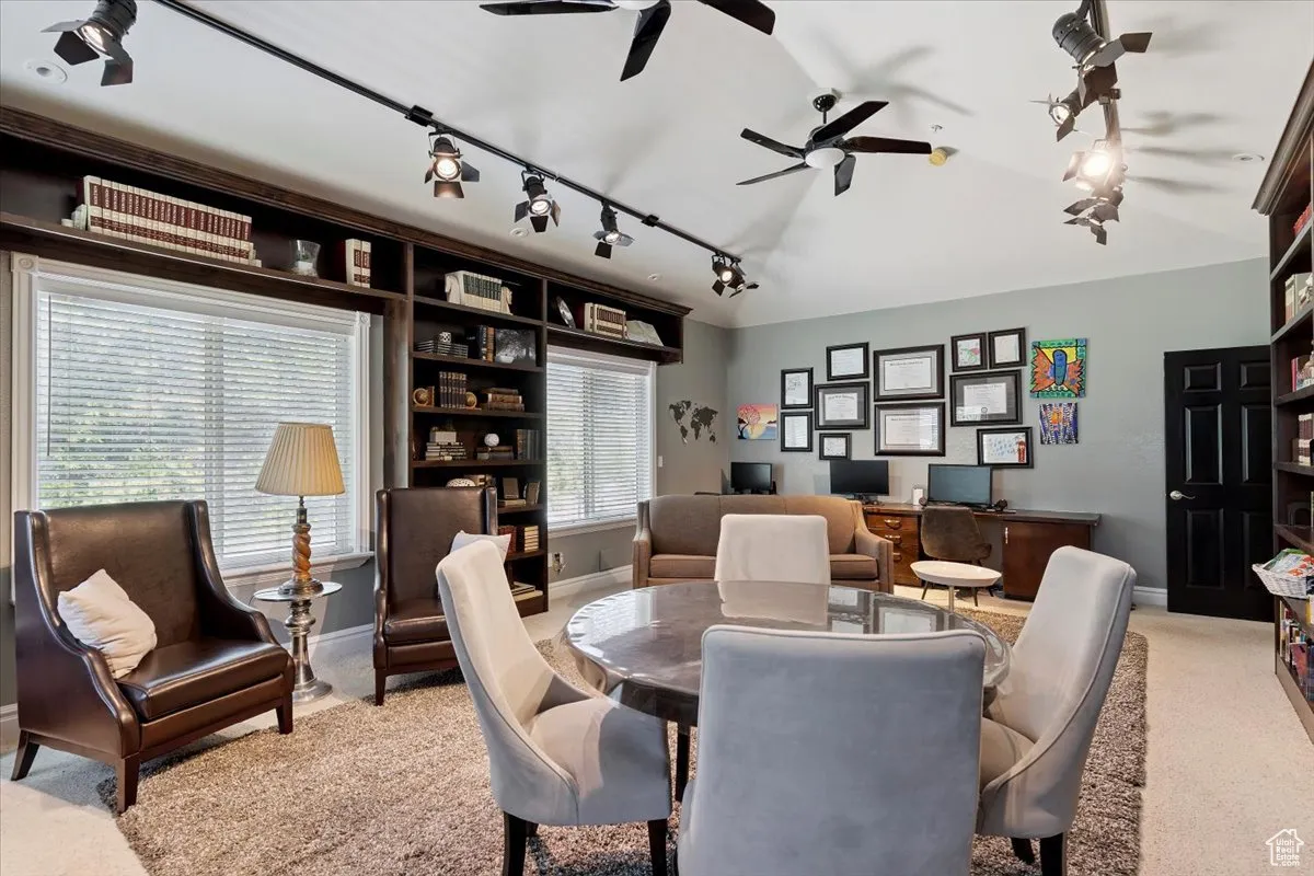 Carpeted dining space with track lighting, a ceiling fan, and a desk