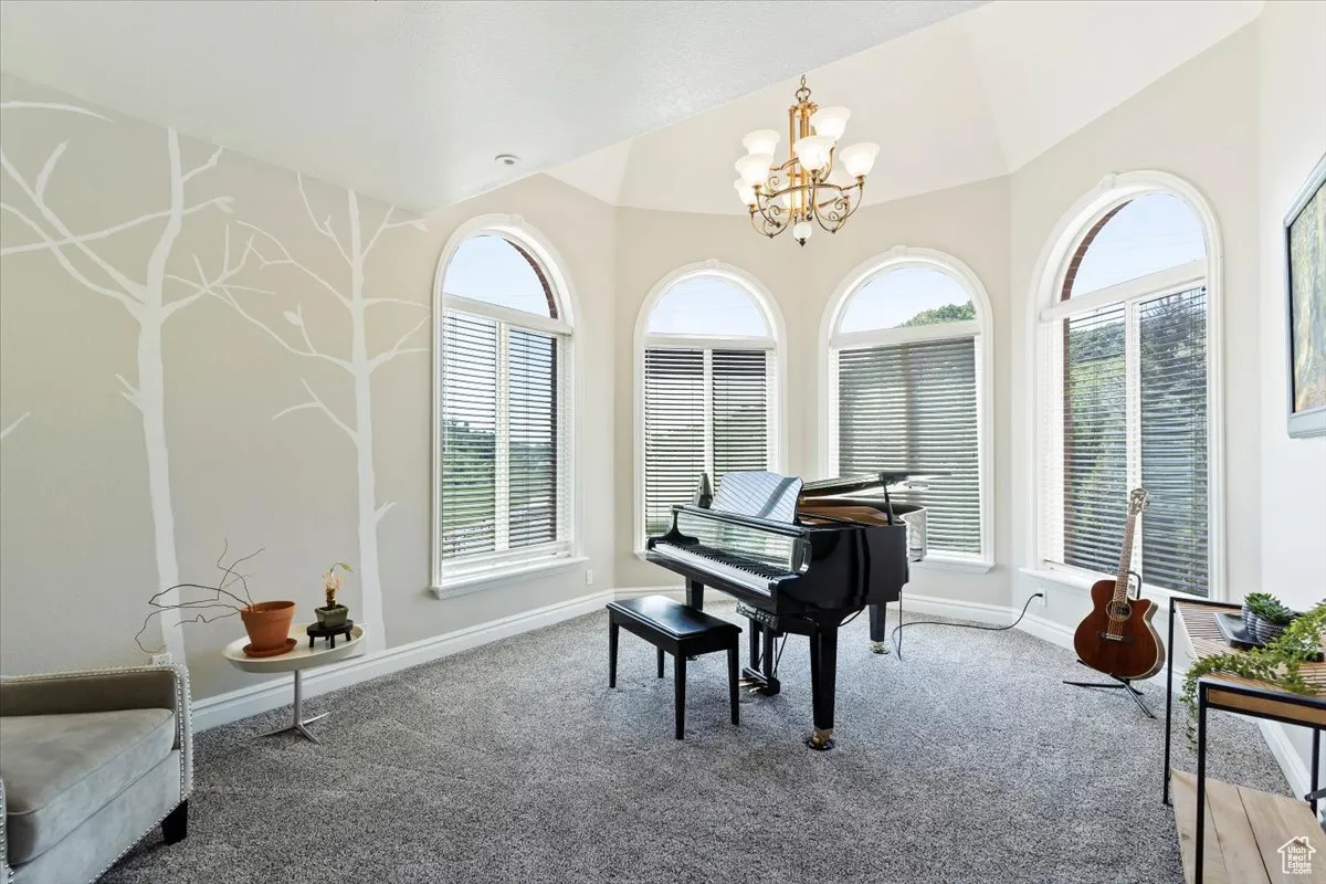 Living area with a chandelier, carpet flooring, and lofted ceiling
