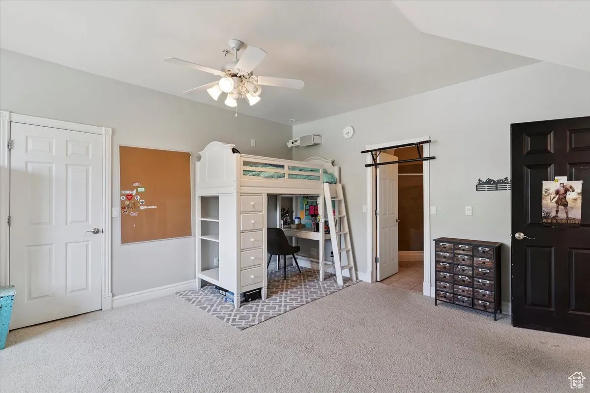 Carpeted bedroom with an office area and a ceiling fan