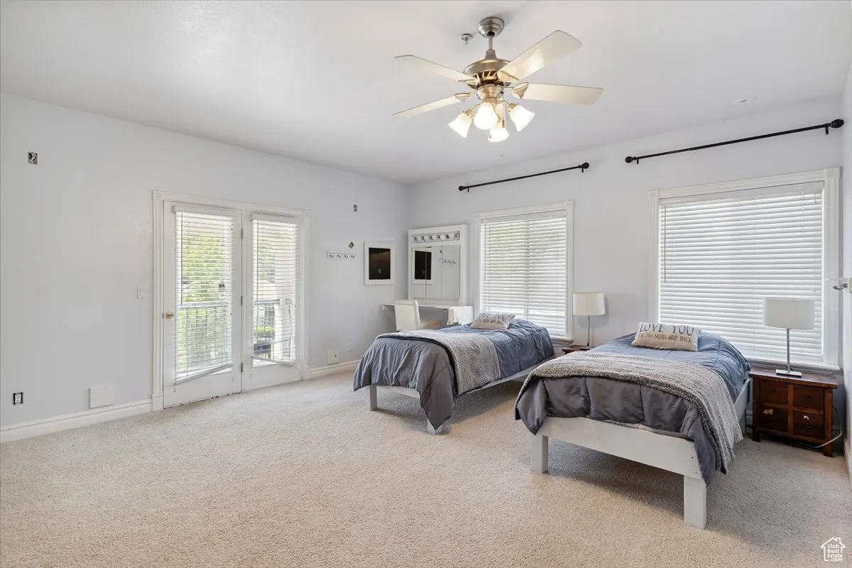 Bedroom with access to outside, carpet floors, multiple windows, and ceiling fan