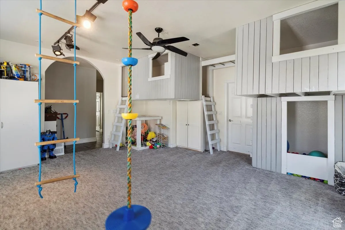 Recreation room featuring ceiling fan, carpet floors, and arched walkways