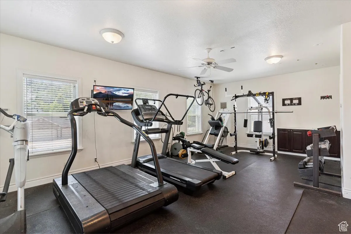 Workout area with a ceiling fan and a textured ceiling