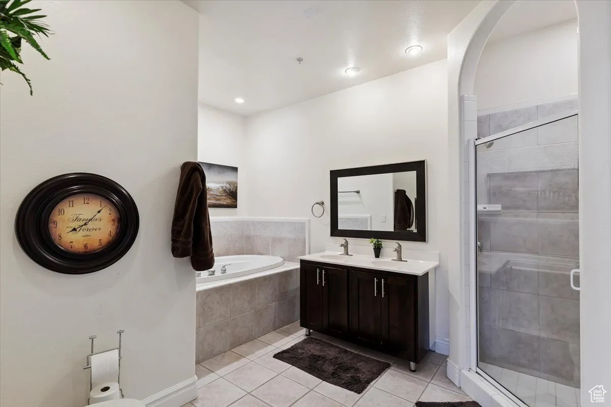 Bathroom featuring tile patterned flooring, a garden tub, a stall shower, and double vanity