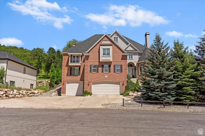 View of front of property featuring a chimney, a garage, driveway, and brick siding