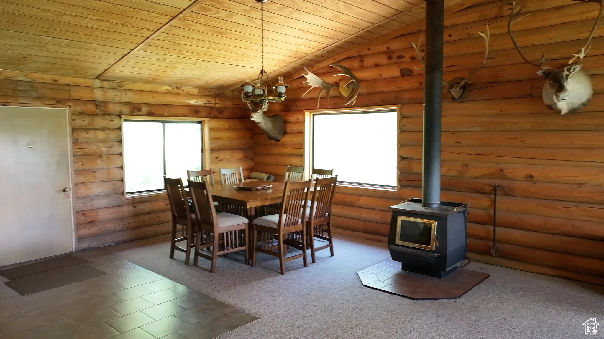 Dining room with wooden ceiling, a wood stove, and log walls