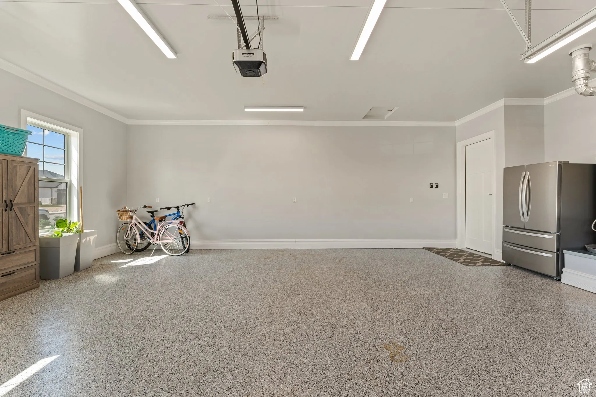 Garage featuring freestanding refrigerator and a garage door opener