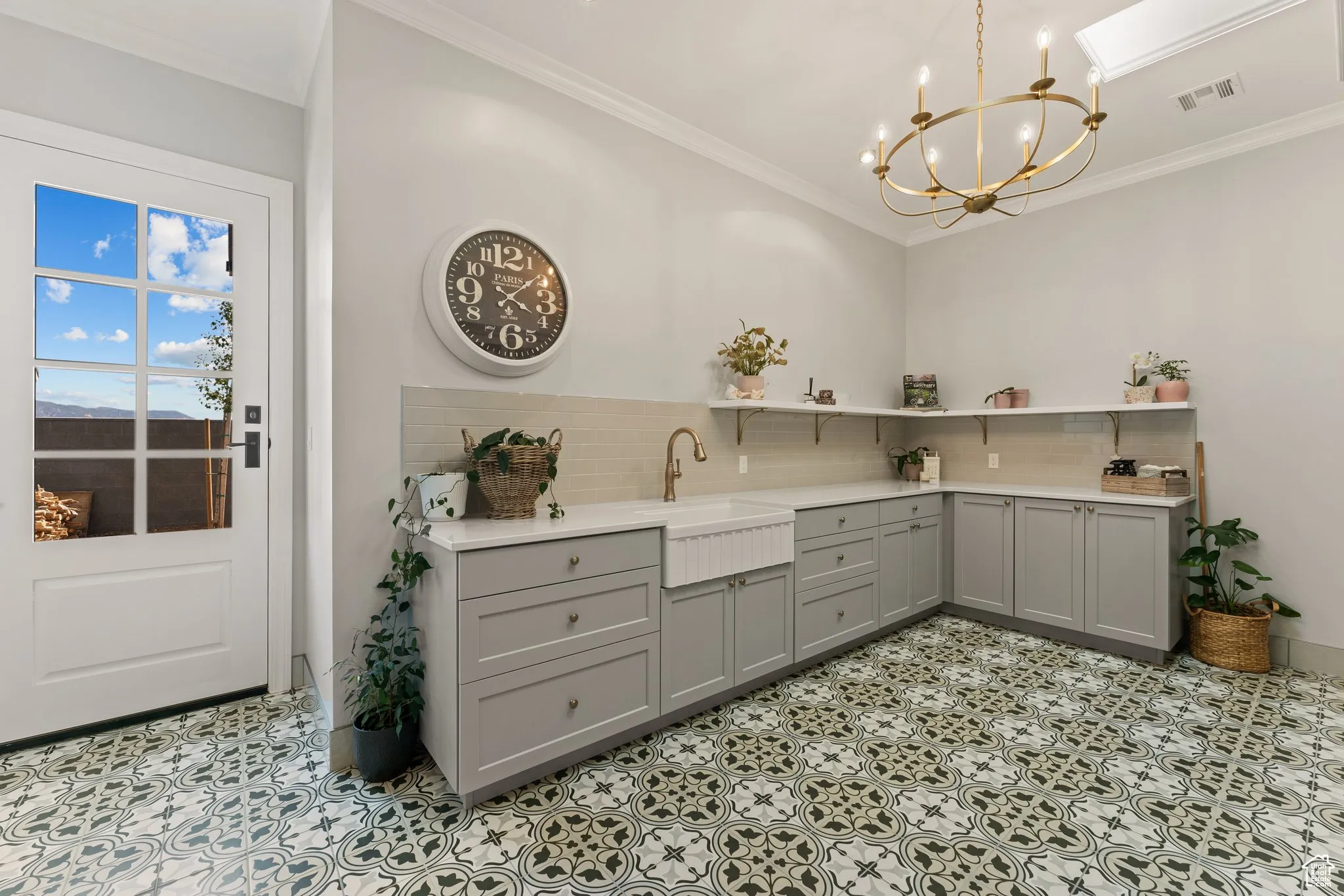 Kitchen with gray cabinets, open shelves, a chandelier, backsplash, and crown molding