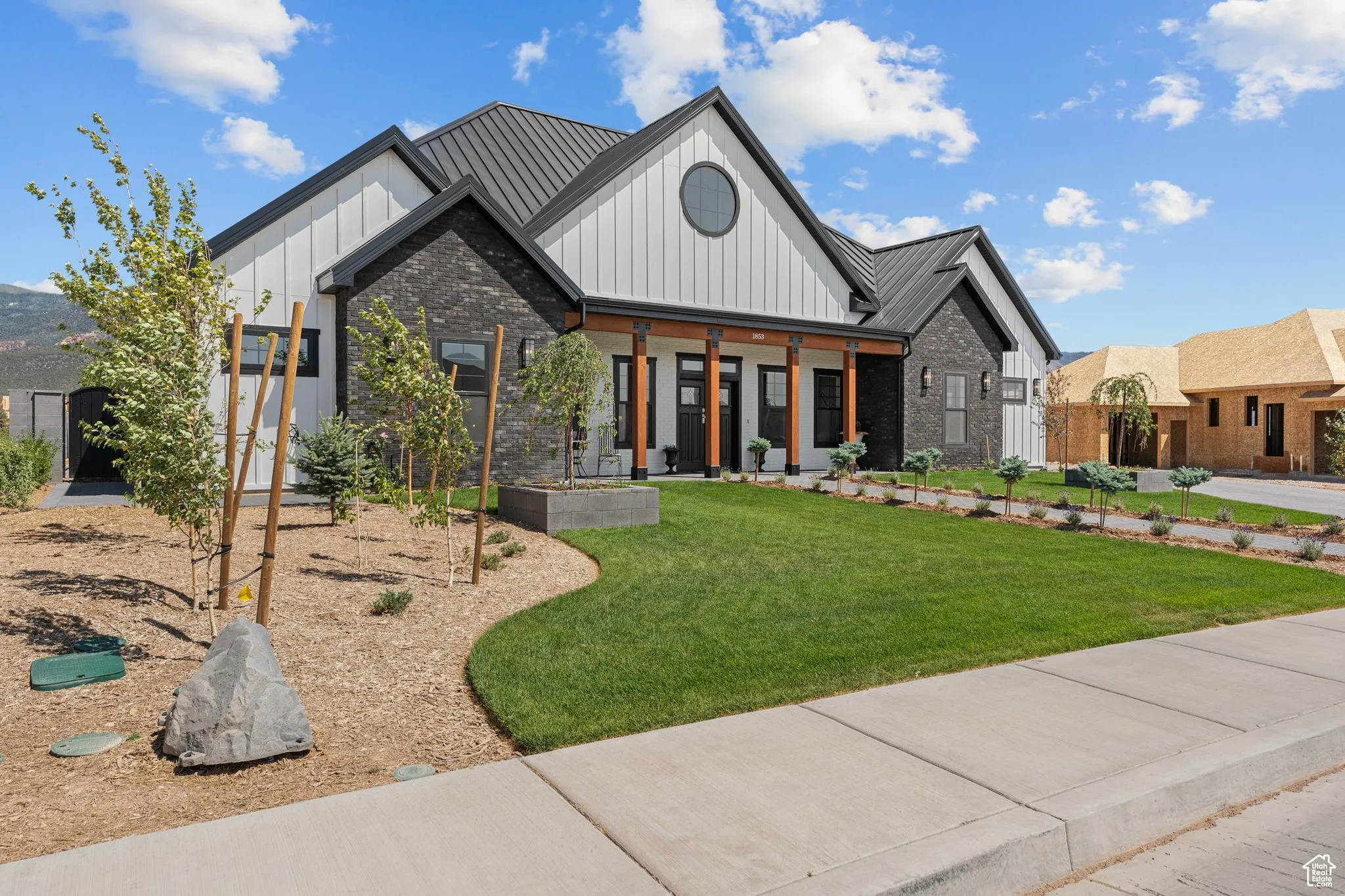 Modern farmhouse featuring board and batten siding, a front yard, and brick siding