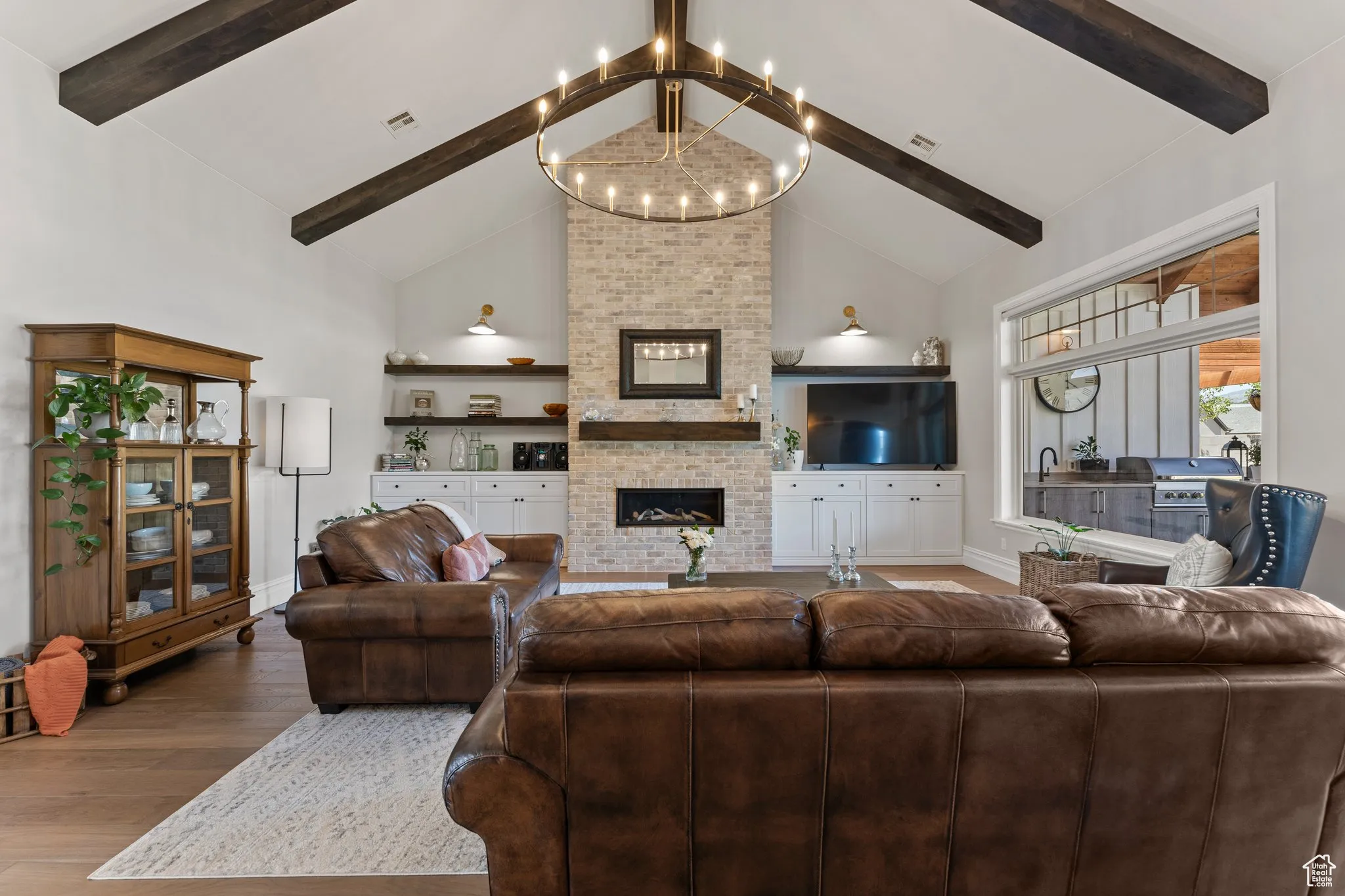 Living area featuring wood finished floors, a chandelier, a fireplace, beam ceiling, and high vaulted ceiling