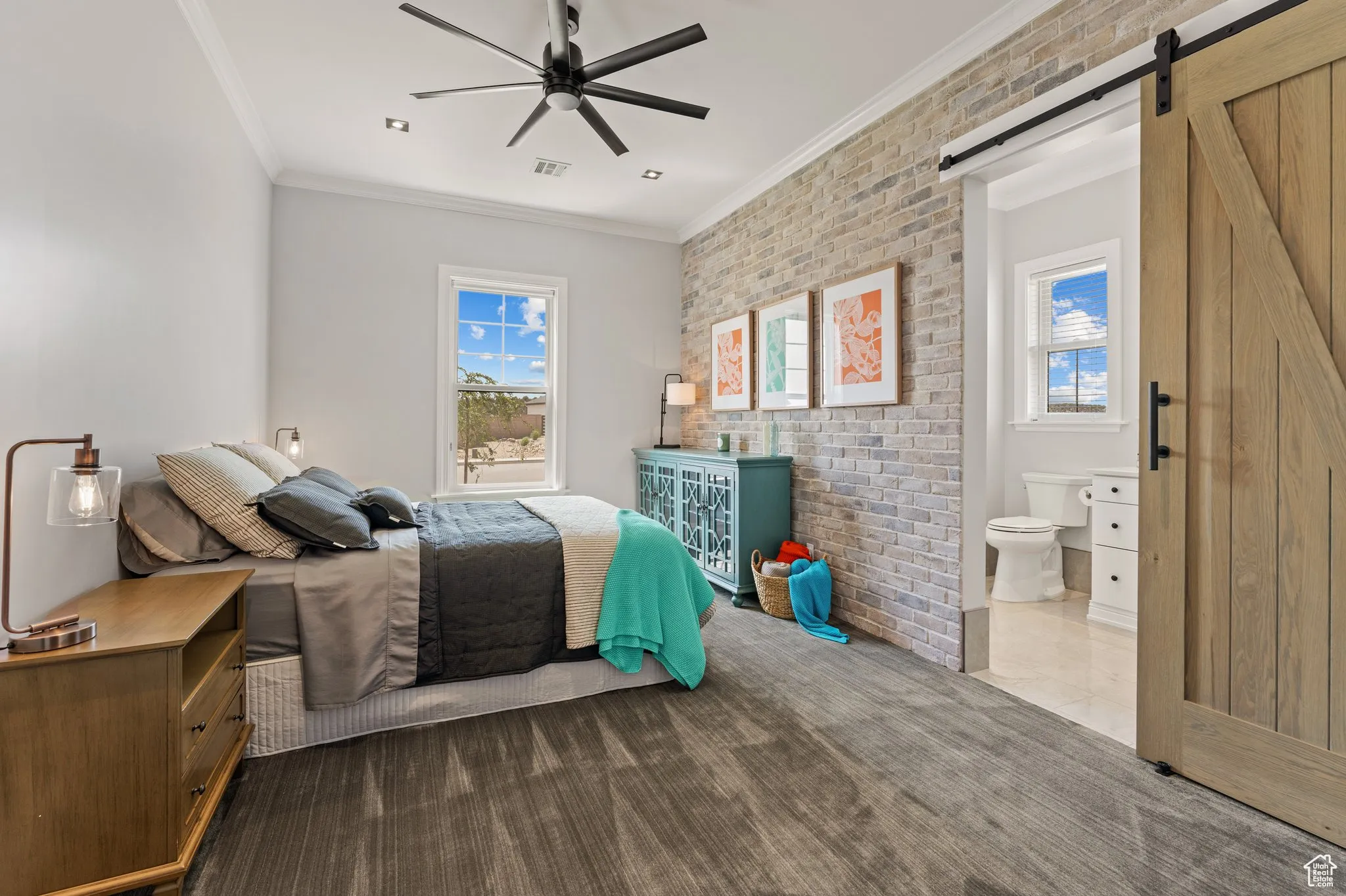 Bedroom with a barn door, brick wall, ornamental molding, carpet, and ceiling fan