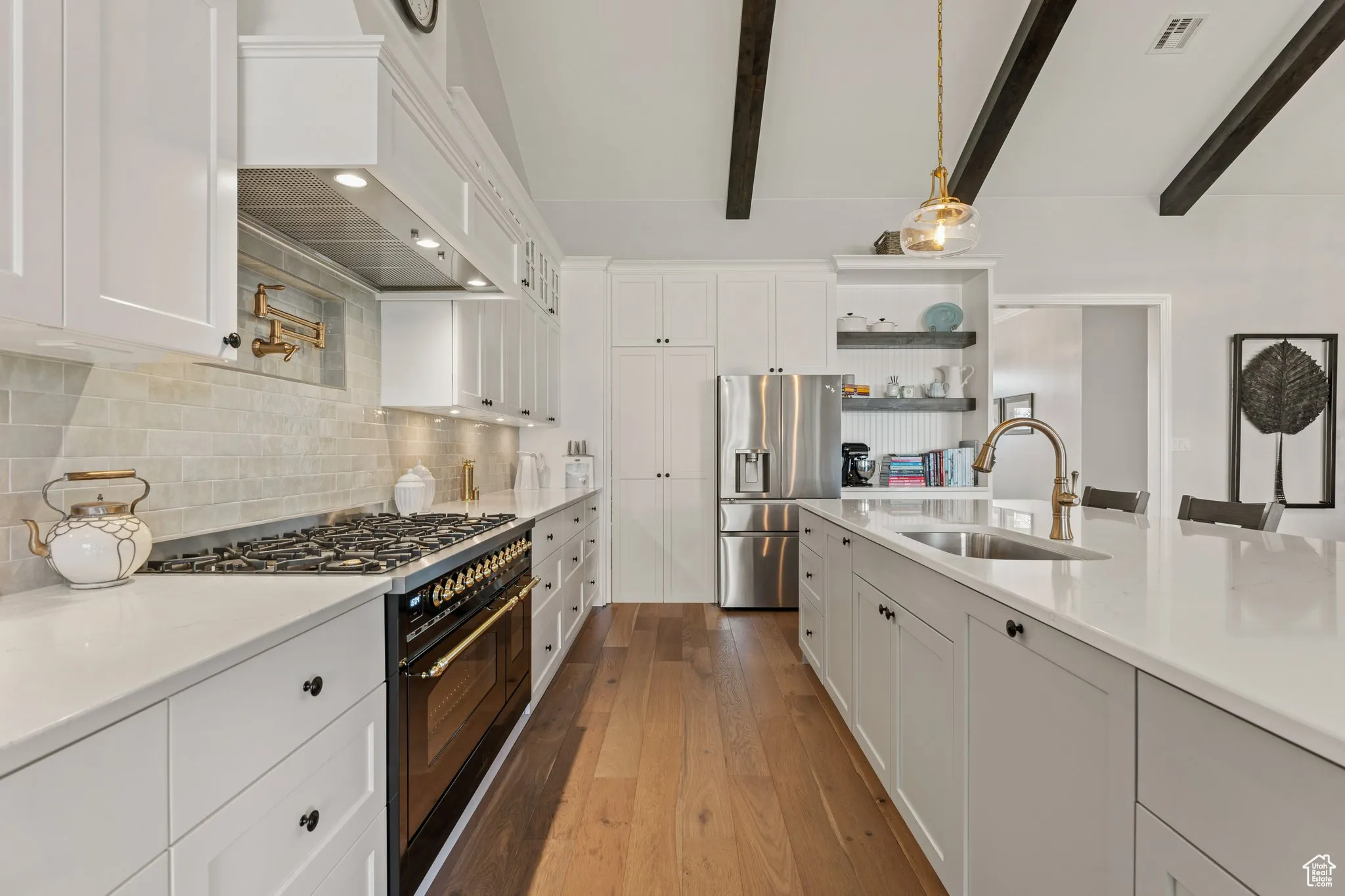 Kitchen featuring range with two ovens, stainless steel refrigerator with ice dispenser, white cabinetry, and hardwood / wood-style flooring