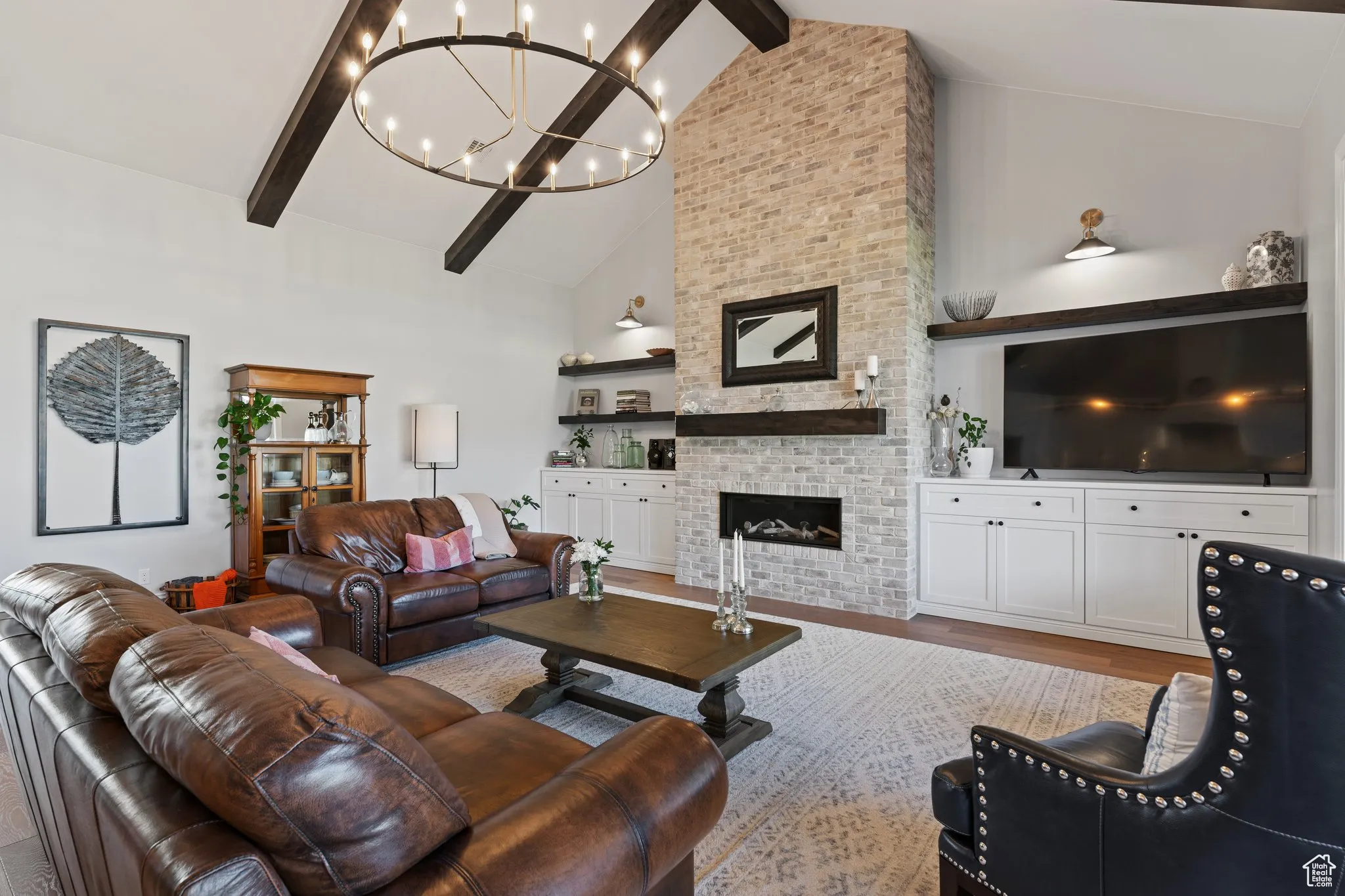 Living room with a chandelier, beam ceiling, a fireplace, wood finished floors, and high vaulted ceiling