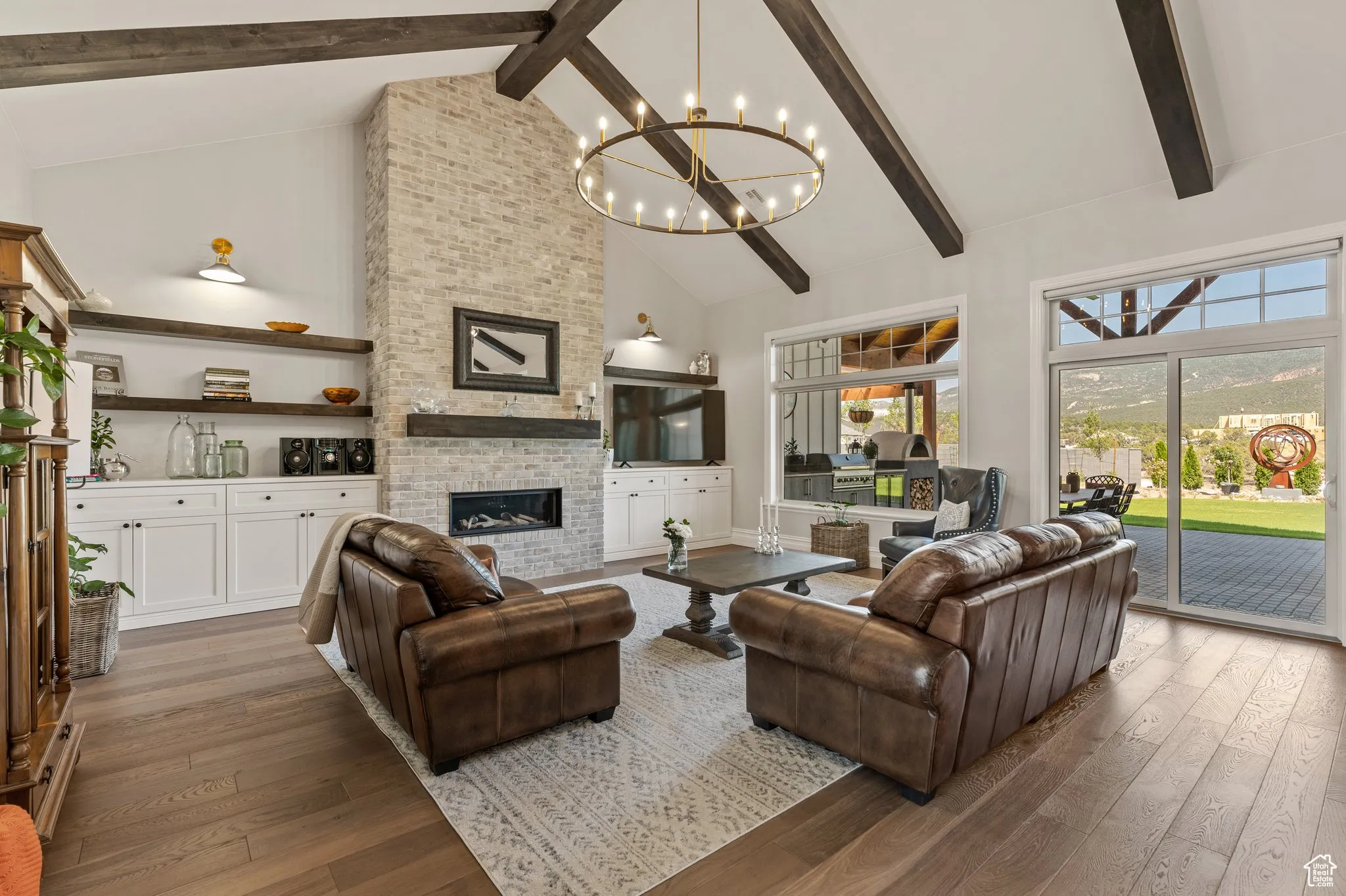 Living area with high vaulted ceiling, a chandelier, beamed ceiling, wood-type flooring, and plenty of natural light