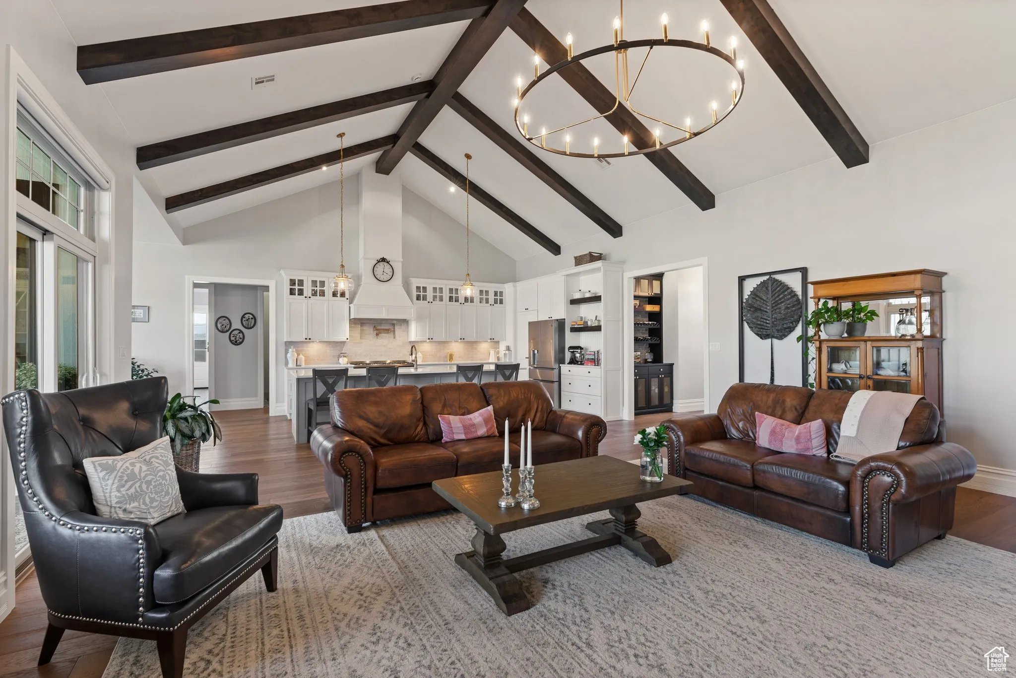 Living room with dark wood finished floors, a chandelier, beamed ceiling, and high vaulted ceiling