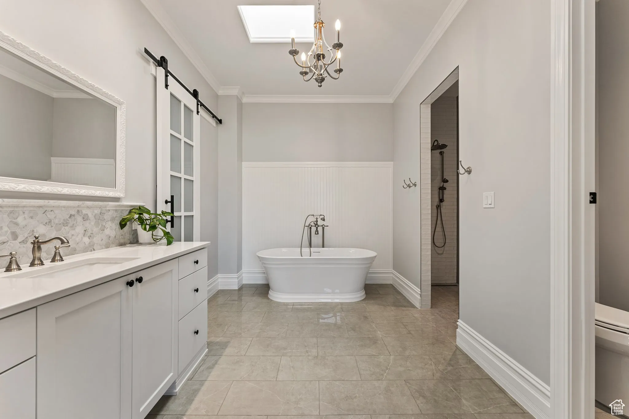 Bathroom featuring vanity, a soaking tub, crown molding, a tile shower, and wainscoting