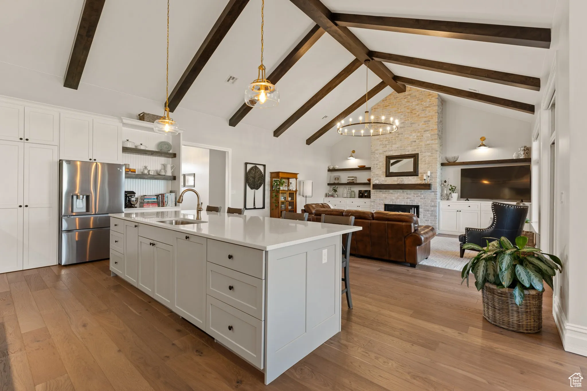 Kitchen with stainless steel refrigerator with ice dispenser, high vaulted ceiling, light countertops, open shelves, and dark wood-type flooring