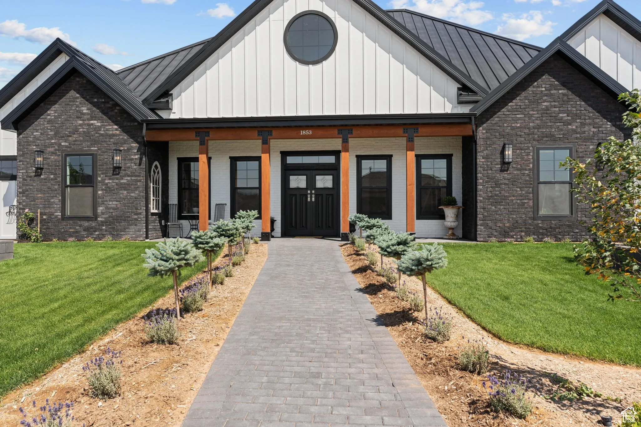 Modern farmhouse style home with board and batten siding, a standing seam roof, and brick siding