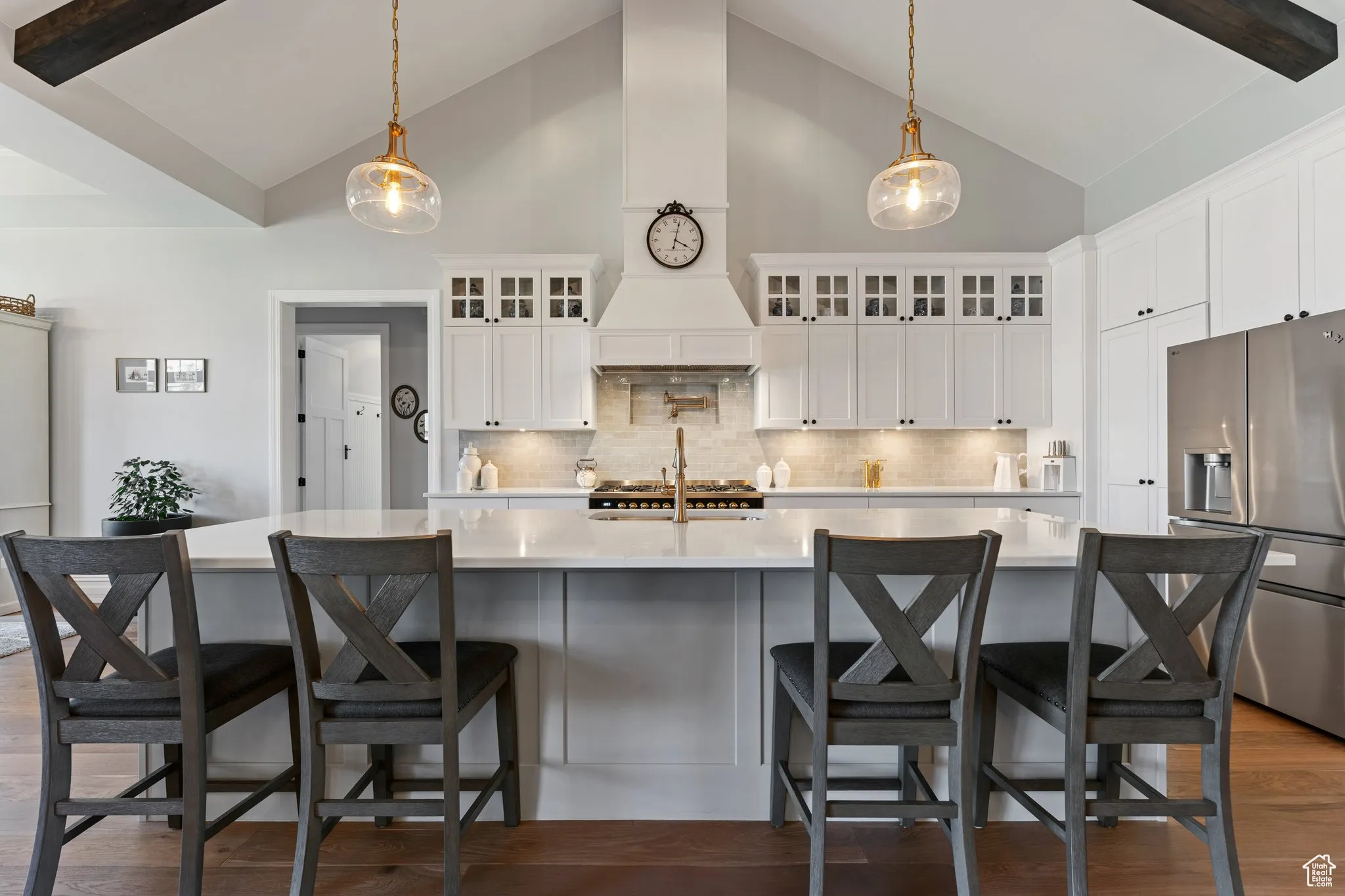 Kitchen with stainless steel fridge with ice dispenser, high vaulted ceiling, light countertops, and tasteful backsplash