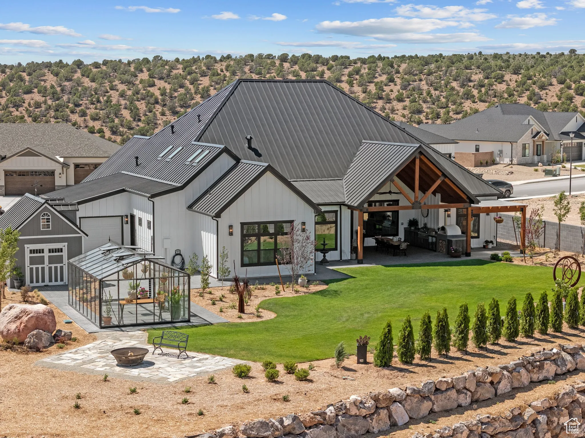 Back of house featuring a fire pit, a patio area, a standing seam roof, a yard, and board and batten siding