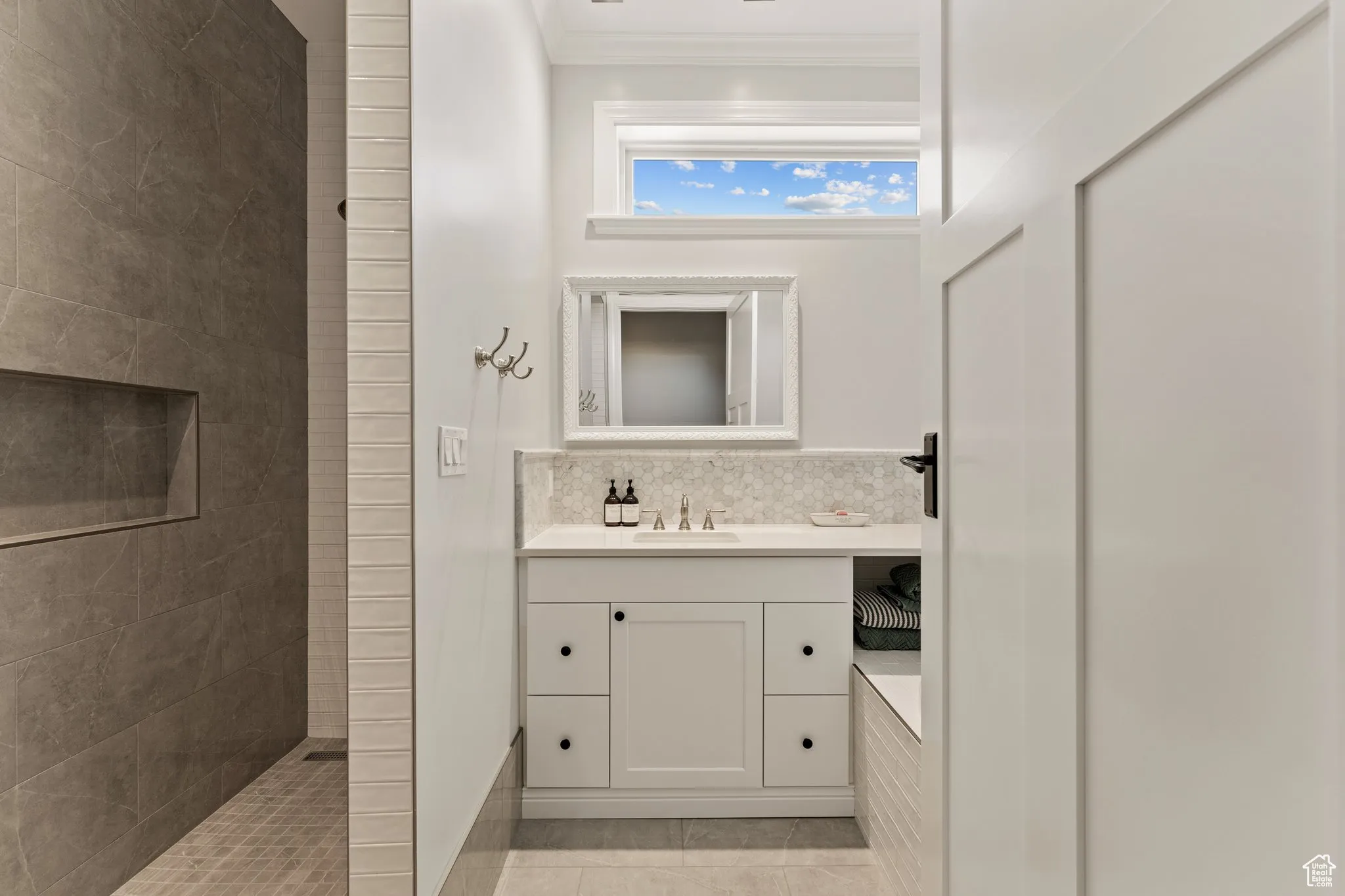 Bathroom with crown molding, vanity, tile patterned floors, and a tile shower