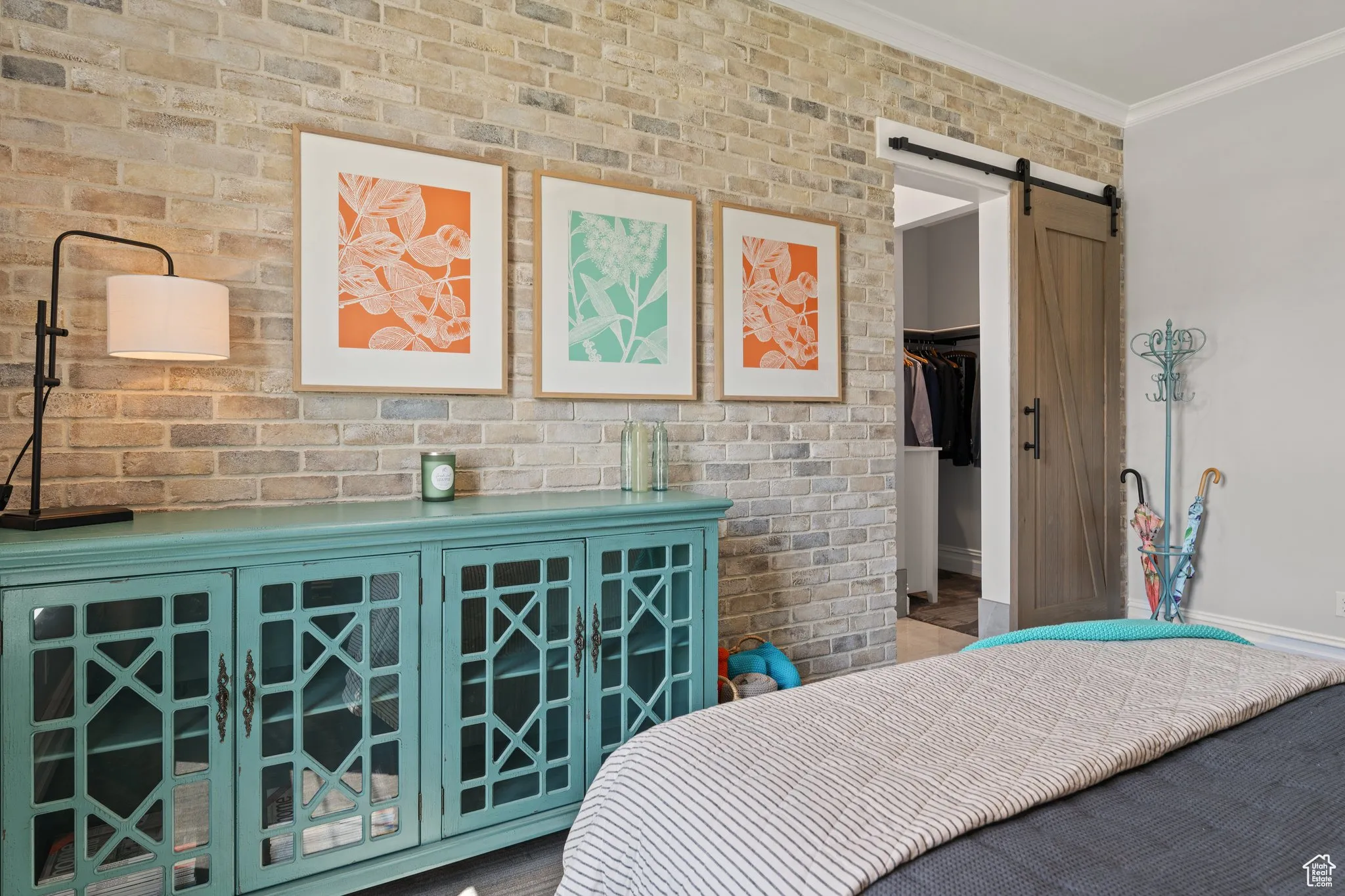 Bedroom with a barn door, ornamental molding, and a spacious closet