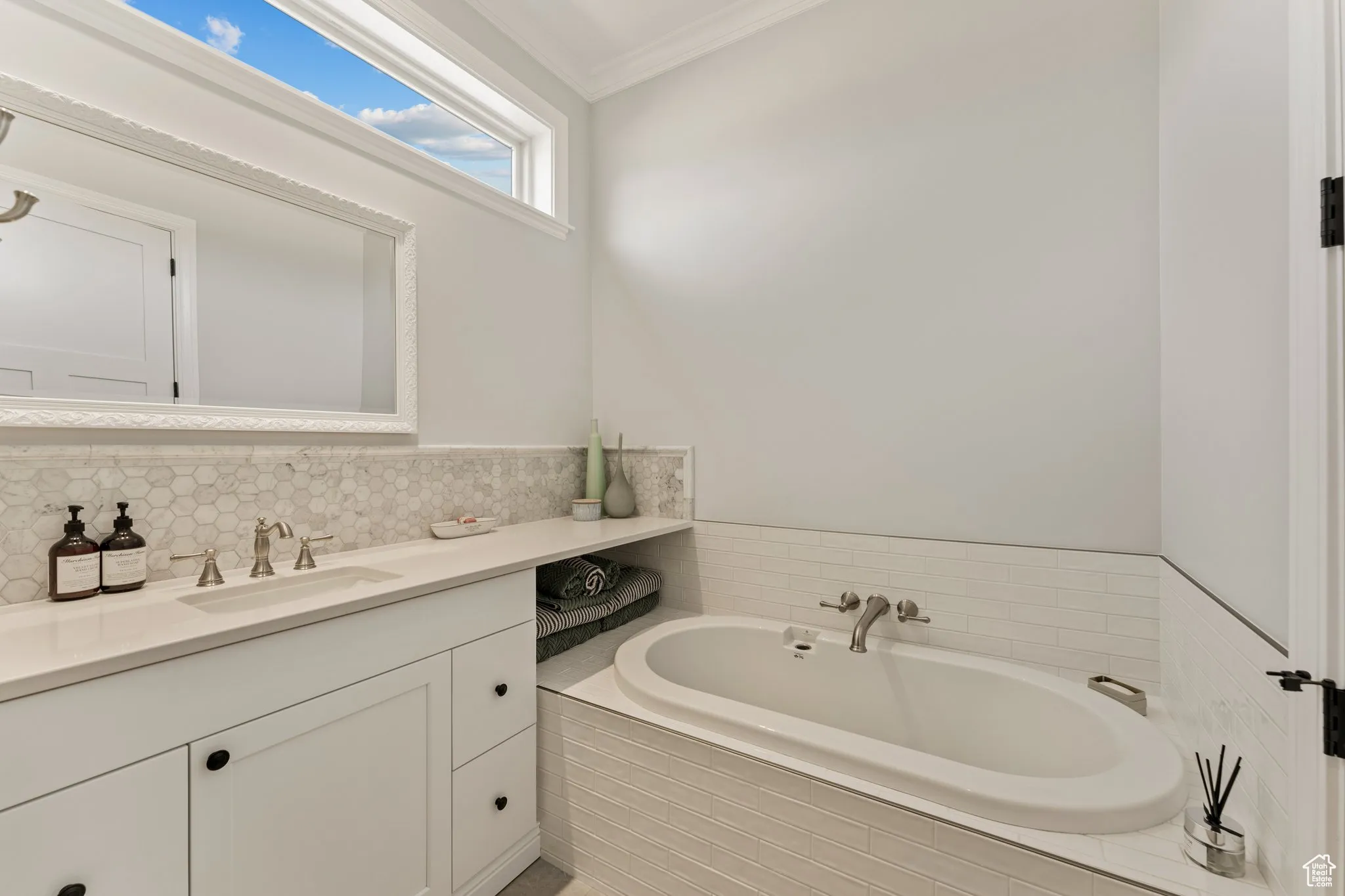 Full bath with crown molding, a garden tub, and vanity