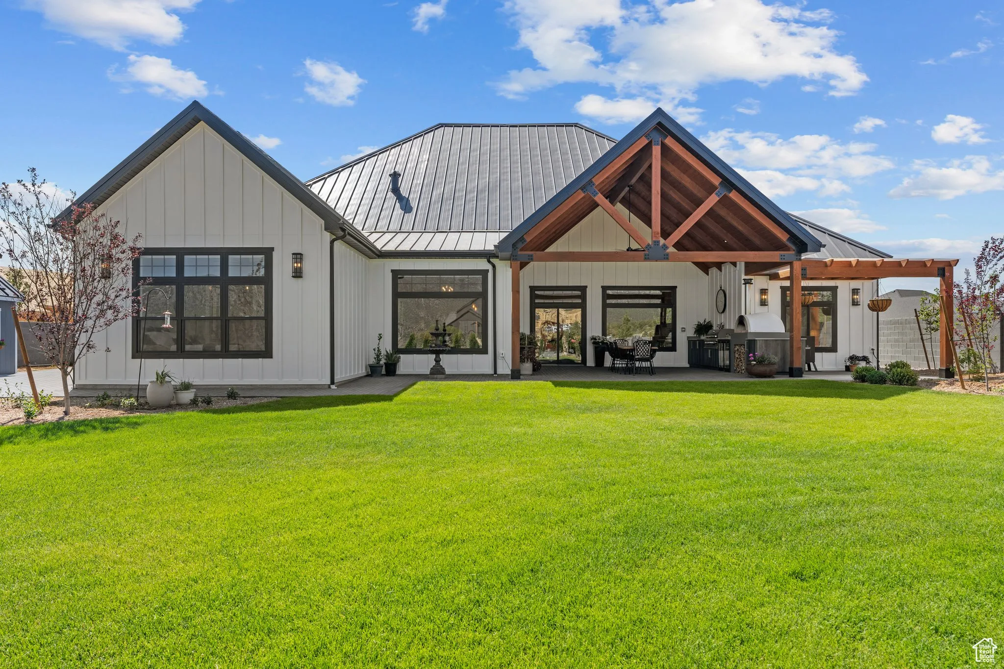 Back of house featuring a standing seam roof, a metal roof, a lawn, and board and batten siding