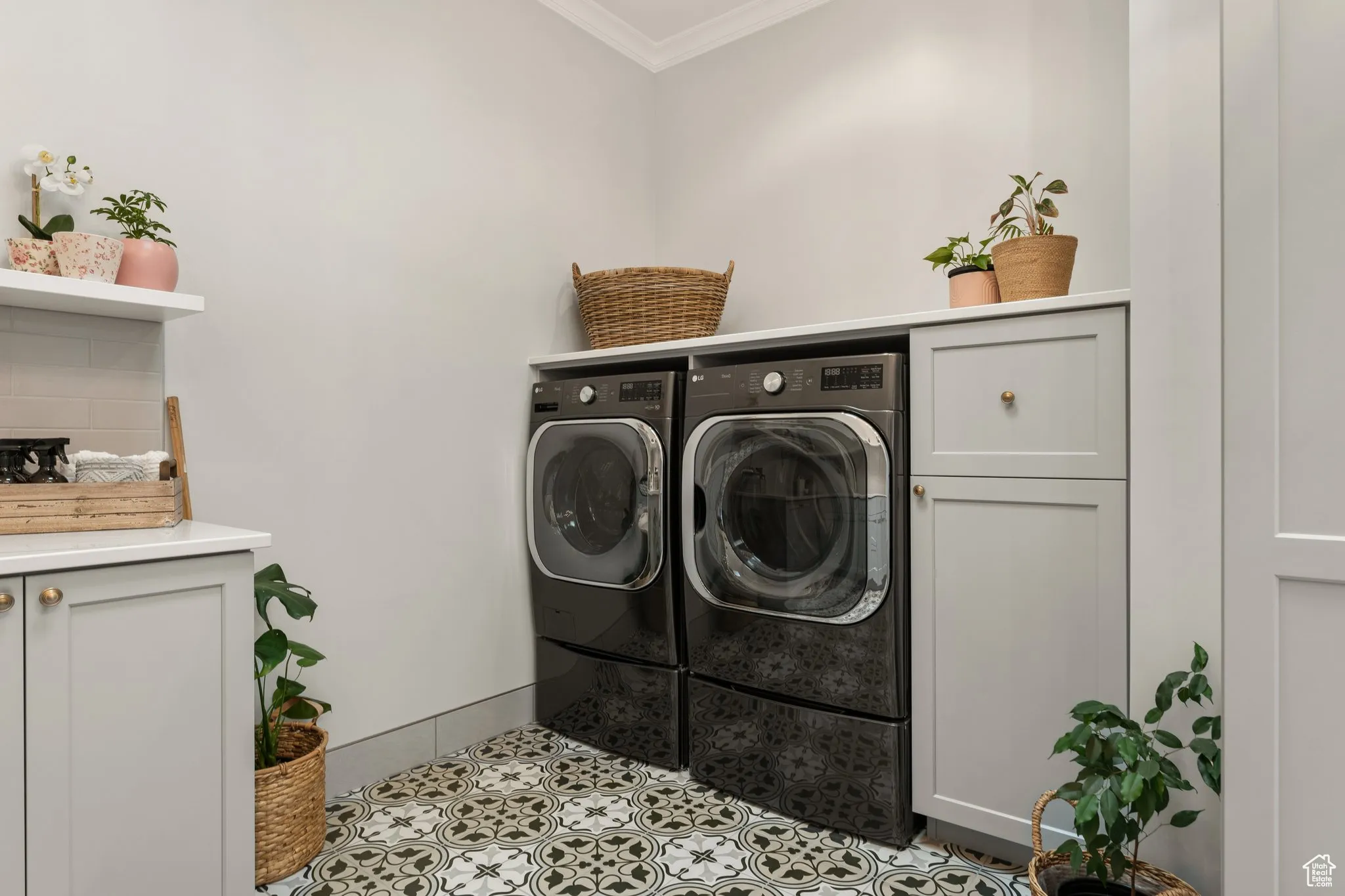 Laundry area with crown molding, washer and dryer, cabinet space, and tile patterned floors