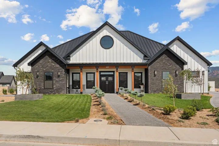 Modern farmhouse style home with board and batten siding, a standing seam roof, and a front lawn