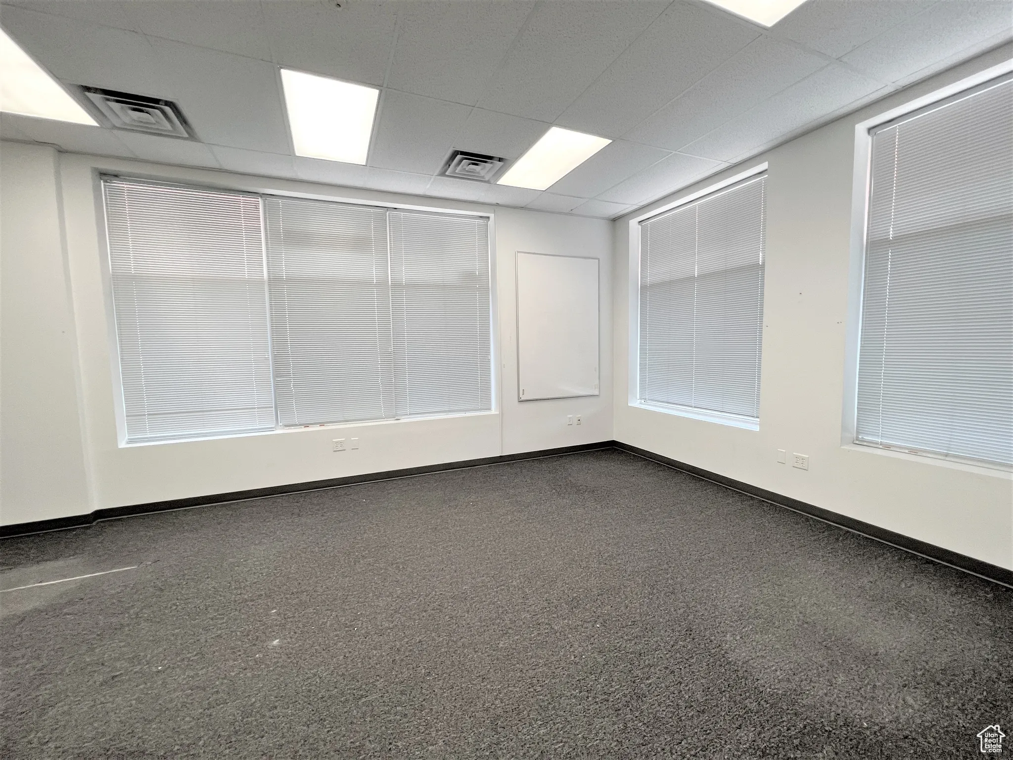 Empty room with a paneled ceiling and dark carpet