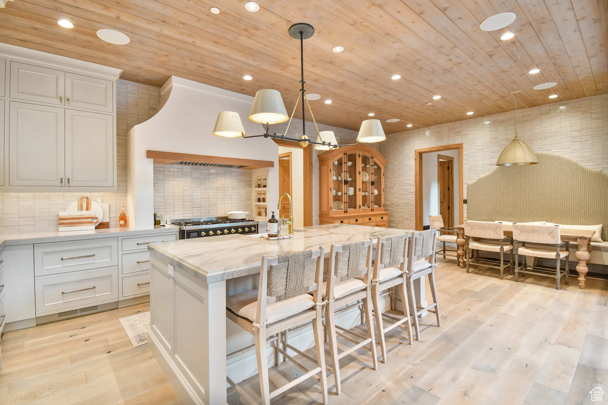 Kitchen featuring wooden ceiling, a center island with sink, white cabinetry, stove, and light wood-style floors