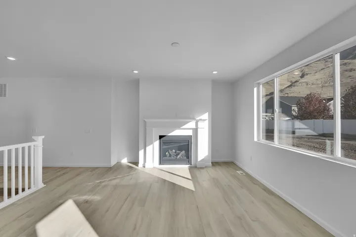 Unfurnished living room with light wood-type flooring, a glass covered fireplace, and recessed lighting