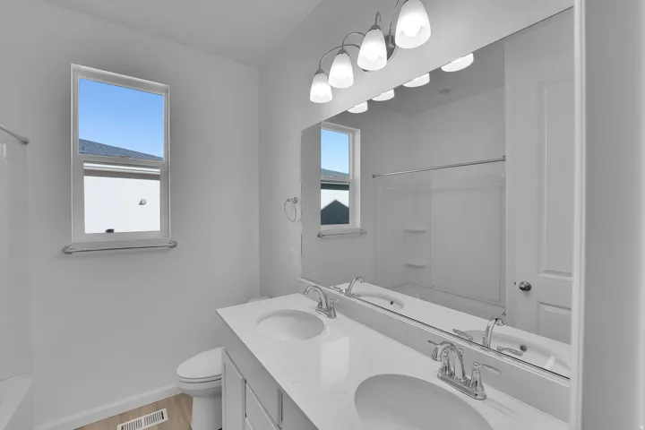 Bathroom with shower / washtub combination, double vanity, and light wood-type flooring