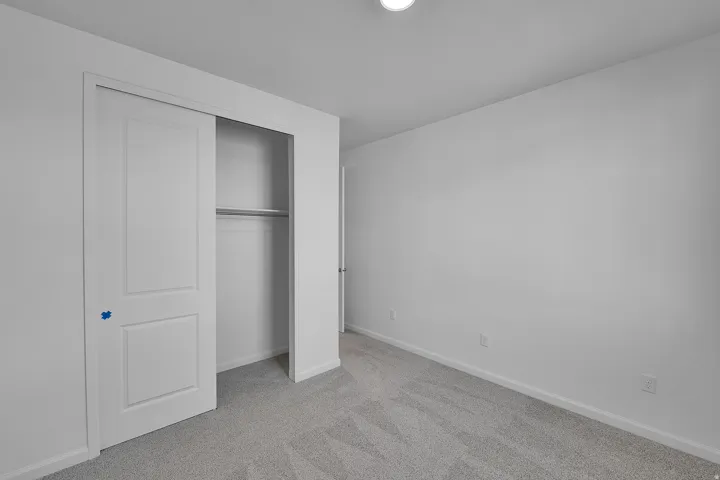 Unfurnished bedroom featuring light colored carpet and a closet