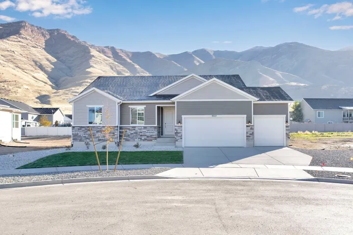View of front facade with a mountain view, driveway, an attached garage, and stone siding