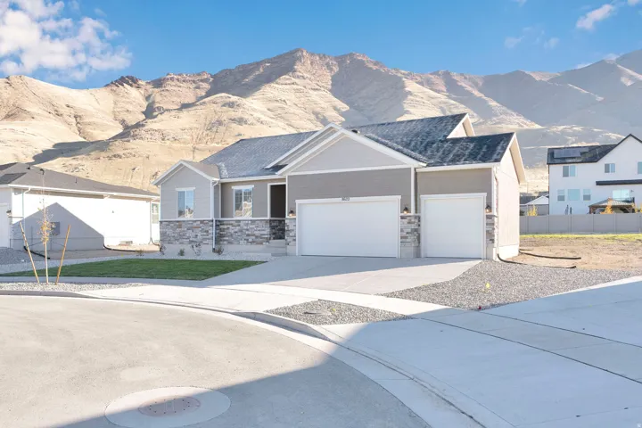 View of front of property featuring a mountain view, driveway, an attached garage, and stone siding