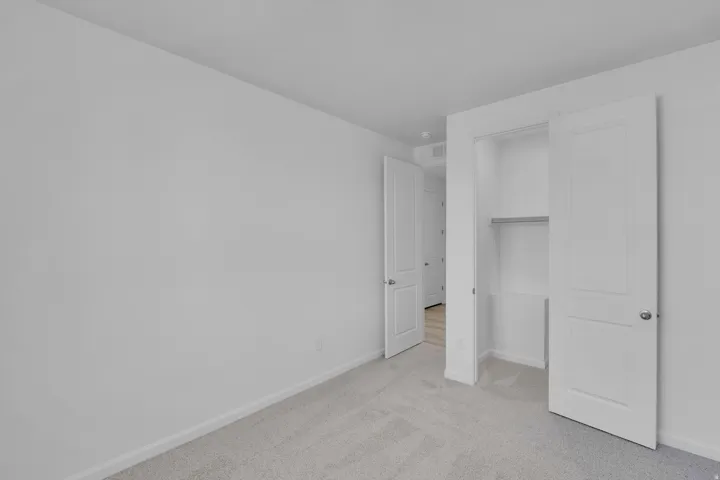 Unfurnished bedroom with light colored carpet and a closet