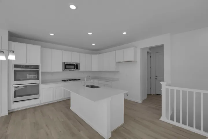 Kitchen featuring white cabinets, appliances with stainless steel finishes, recessed lighting, a kitchen island with sink, and light wood-style floors