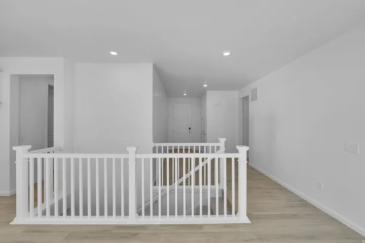 Hallway featuring an upstairs landing, light wood finished floors, and recessed lighting