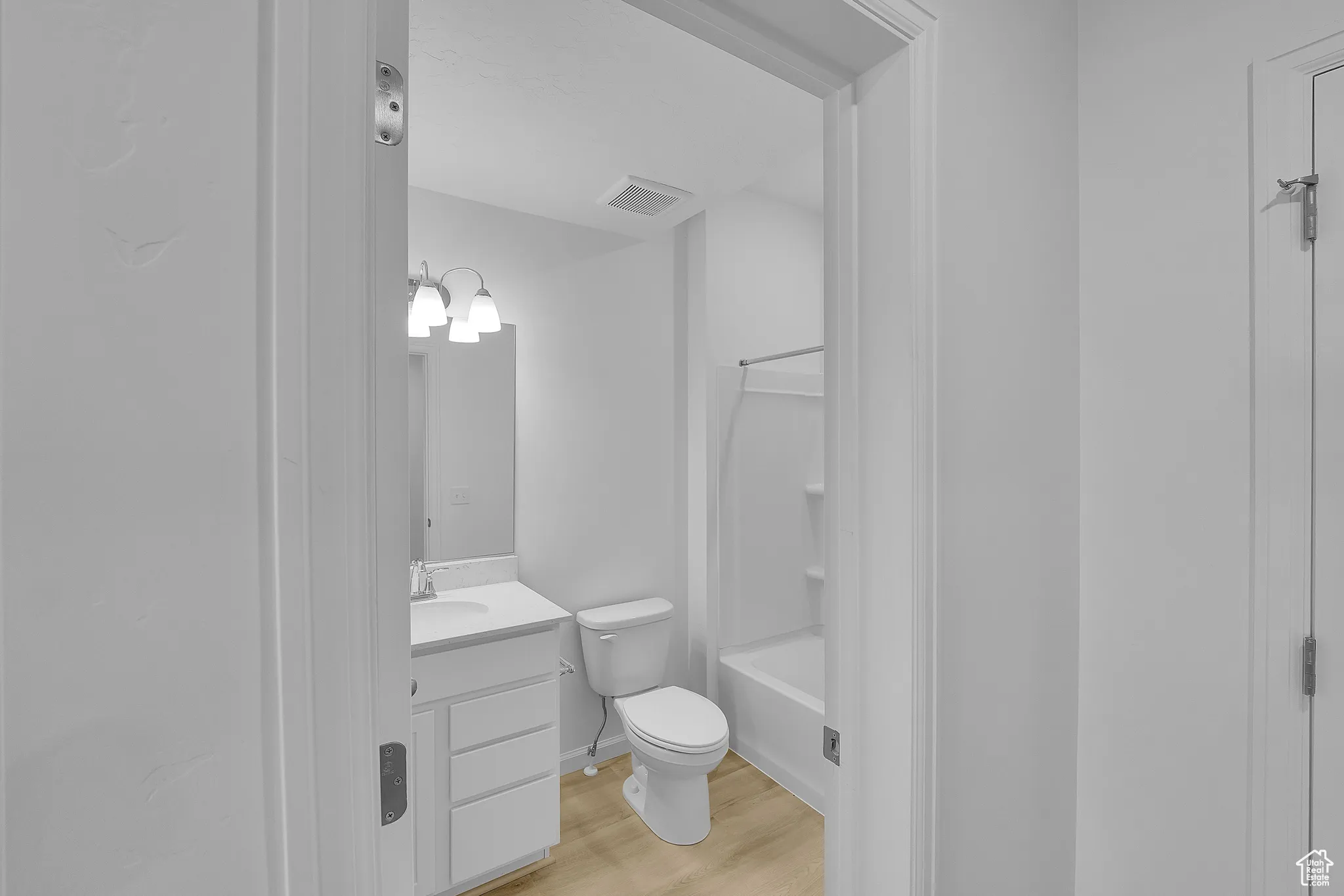 Full bathroom with light wood finished floors, vanity,  shower combination, and a chandelier