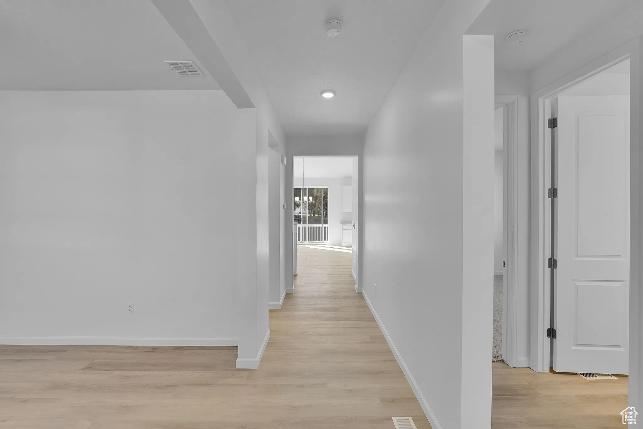 Hallway with light wood-type flooring, recessed lighting, and a chandelier