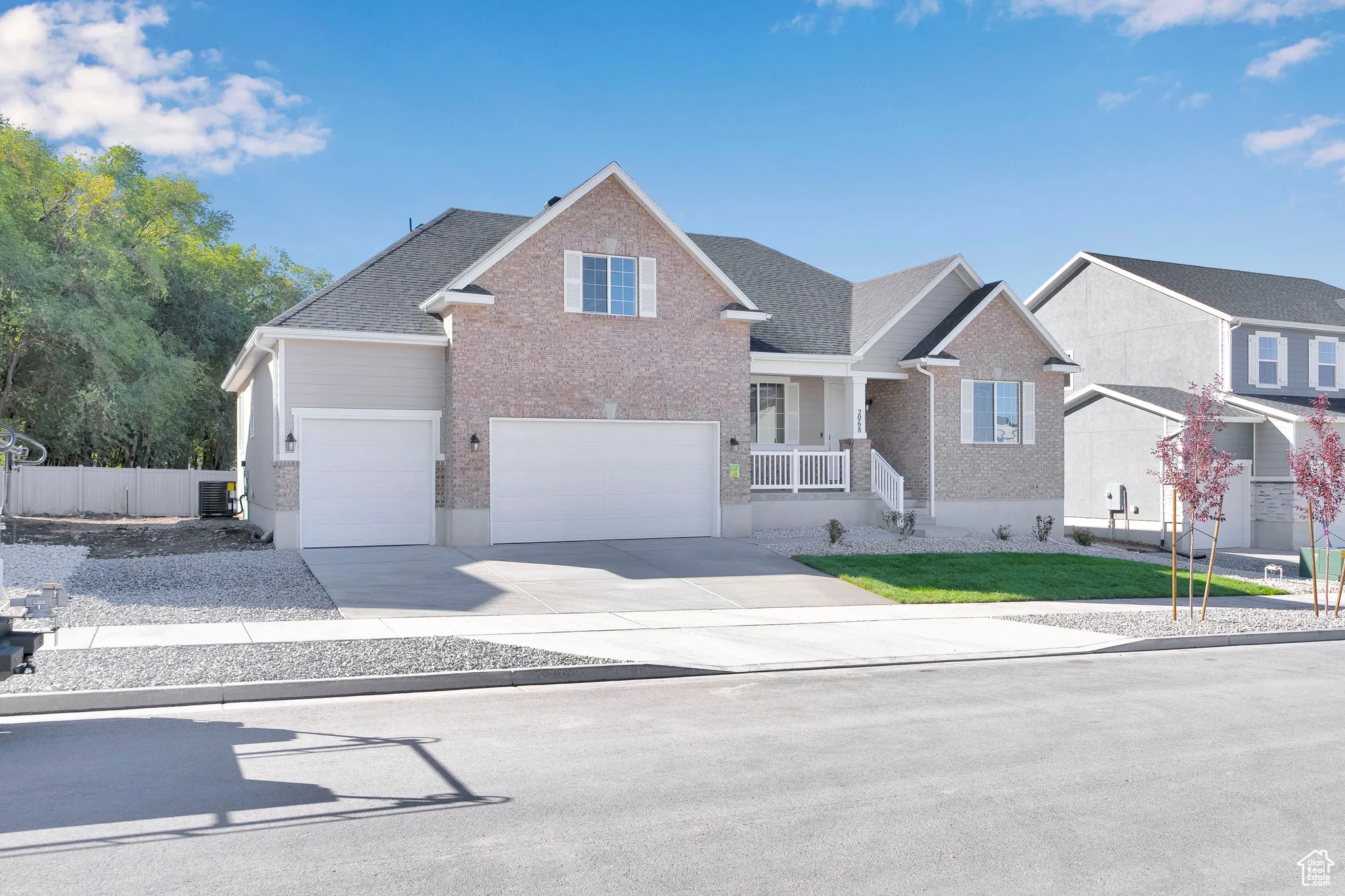 View of front of property with a porch, brick siding, driveway, a garage, and roof with shingles