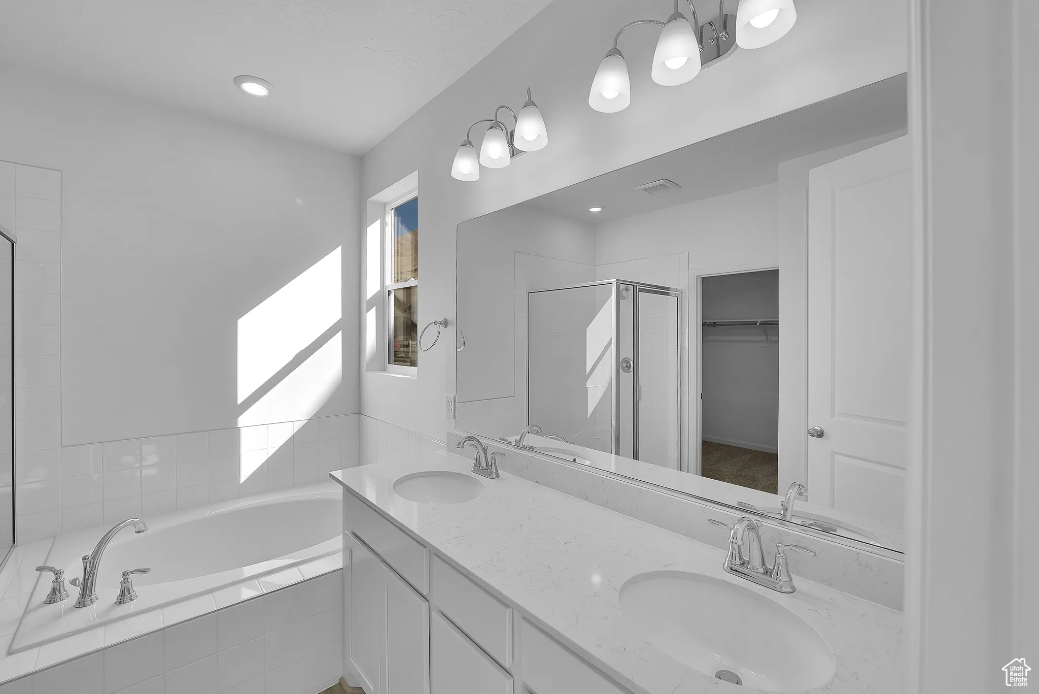Bathroom with a stall shower, a spacious closet, a garden tub, double vanity, and recessed lighting