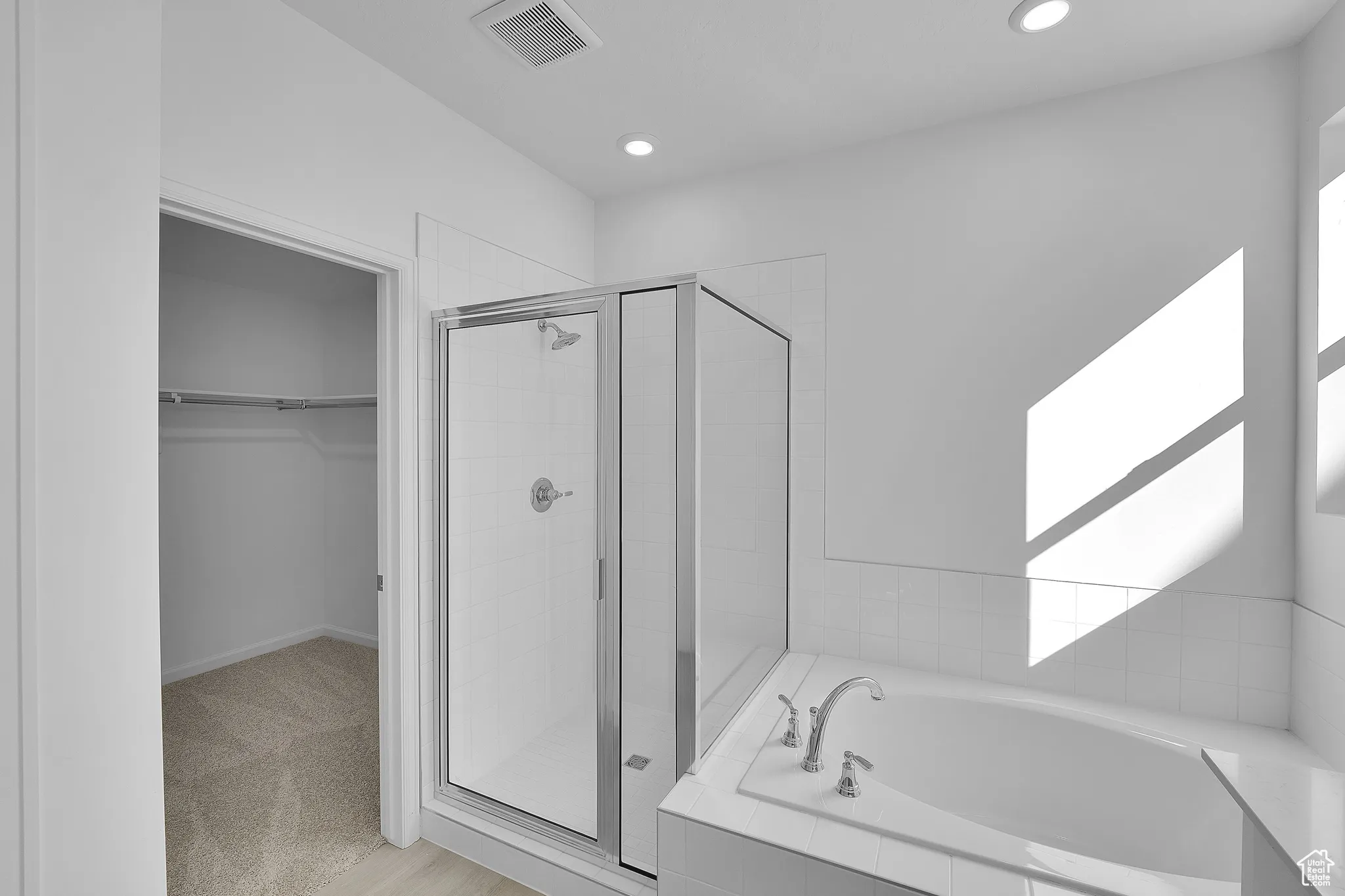 Bathroom with a shower stall, a spacious closet, a bath, and recessed lighting